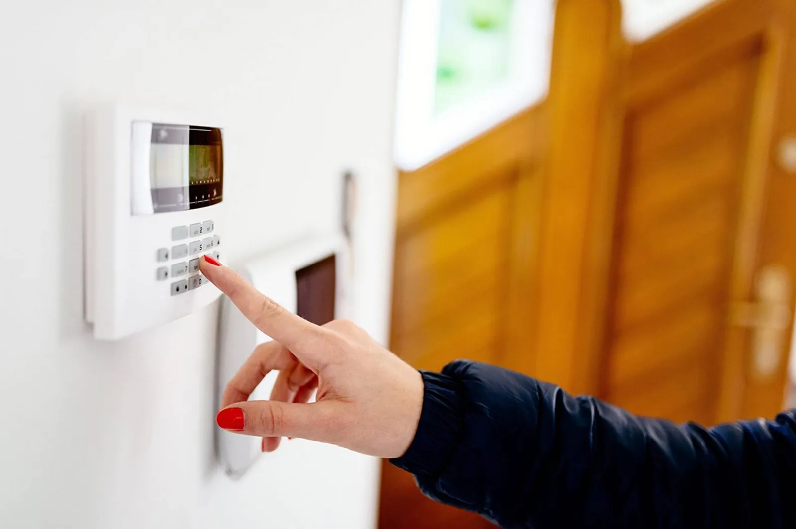 Wireless intruder alarm control panel being armed on a wall